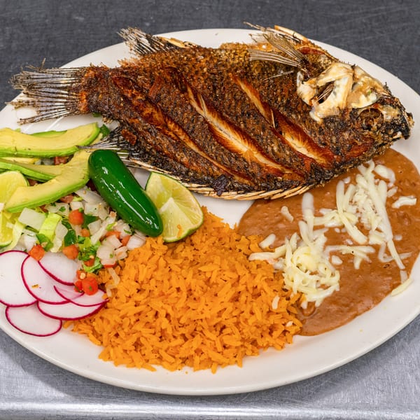 Whole fried fish with rice, refried beans, avocado, pico de gallo, radish, lime, and jalapeño.