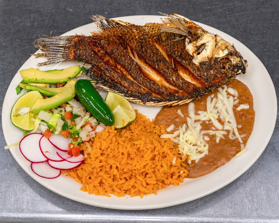 Whole fried fish with rice, refried beans, avocado, pico de gallo, radish, lime, and jalapeño.