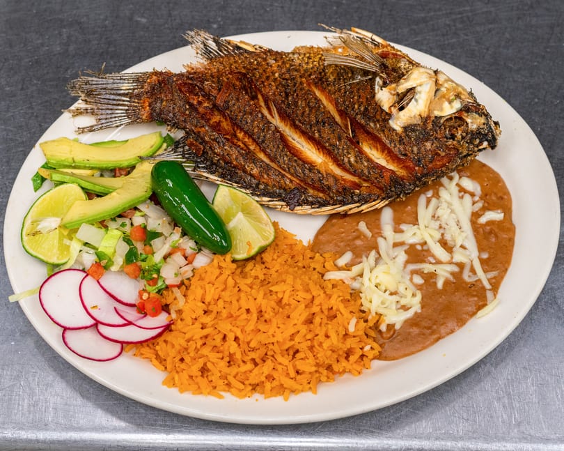 Fried whole fish with rice, refried beans, avocado, pico de gallo, radish, lime, and jalapeño.