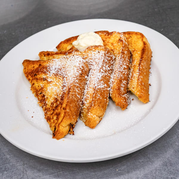 Golden-brown French toast slices, dusted with powdered sugar and topped with a dollop of butter.