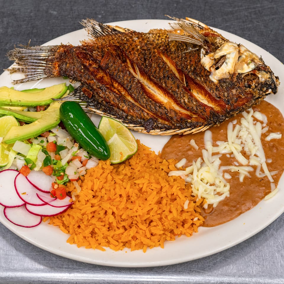 Fried whole fish with rice, refried beans, avocado, radishes, lime, and pico de gallo.